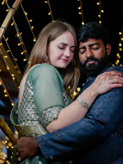 An intimate embrace between the couple, with the warm glow of reception lights in the background.