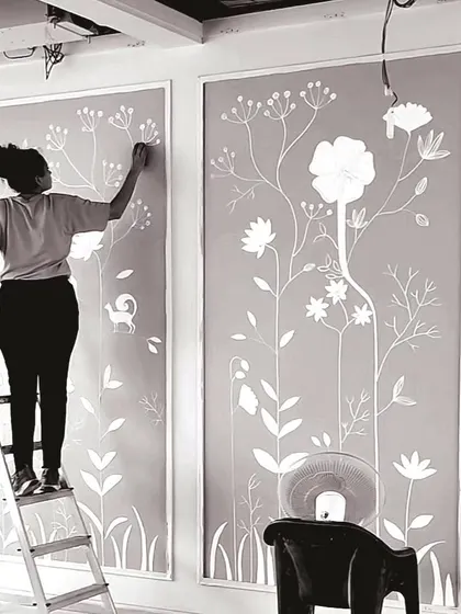 A black and white photo of me on a ladder, working on a 3D texture mural. This is a glimpse into my eventful journey.
