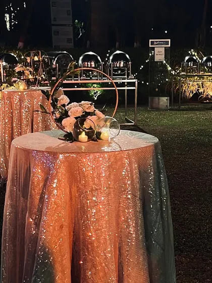A sequined tablecloth and a simple floral centerpiece on a cocktail table. These details add a touch of glamour and sparkle to the guest areas during the sangeet night.