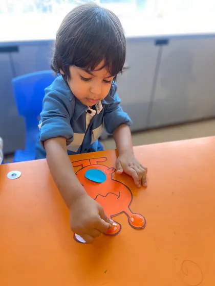 Another angle showing the careful placement of googly eyes on a craft. These details matter to the children and we celebrate their precision.