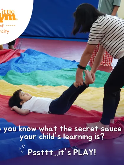 The secret sauce to learning is play! An instructor helps a child with a fun parachute exercise that builds core strength and trust.