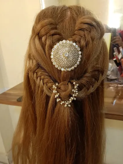 A creative half-up style with braided details and a large, sparkling centerpiece.