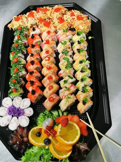 A lavish sushi platter offering a wide variety for guests. It includes different types of maki rolls, nigiri, and fresh fruit, beautifully arranged for a buffet or sharing-style meal.