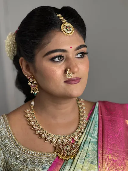 A classic bridal portrait. The focus is on the defined eyes and the soft, matte lip color that complements her traditional attire.