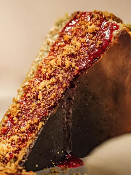 A dramatic close-up of a cheesecake slice, focusing on the glistening jam topping and crumbly texture. Macro shots like this highlight the details that make a dessert special.