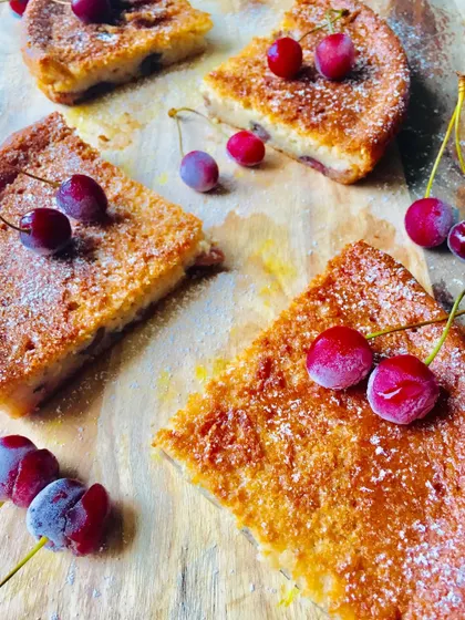 An overhead shot of the sliced vegan cherry lime cake, decorated with fresh and frozen cherries. It looks as refreshing as it tastes.
