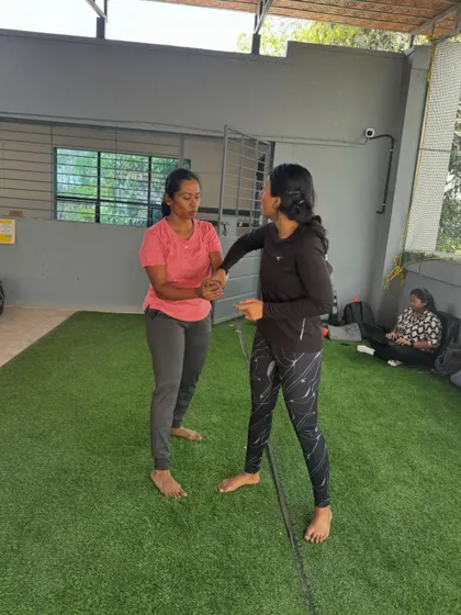 Two women practicing a wrist lock technique. This move is designed to control an aggressor's arm and create an opportunity to escape.