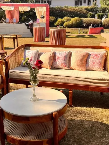 A comfortable and stylish lounge corner. The seating arrangement combines natural wood and cane textures with soft, pastel-colored cushions for a relaxed yet chic vibe.