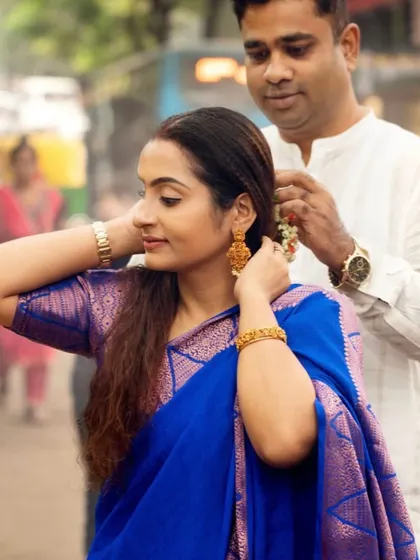 A small, intimate gesture captured outdoors. A husband gently placing flowers in his wife's hair is a beautiful, romantic moment that tells a story of care and affection.