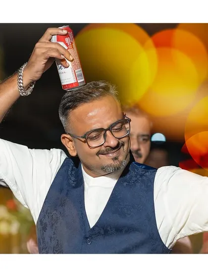 Candid moments where joy meets rhythm. A guest having fun on the dance floor, balancing a can on his head.