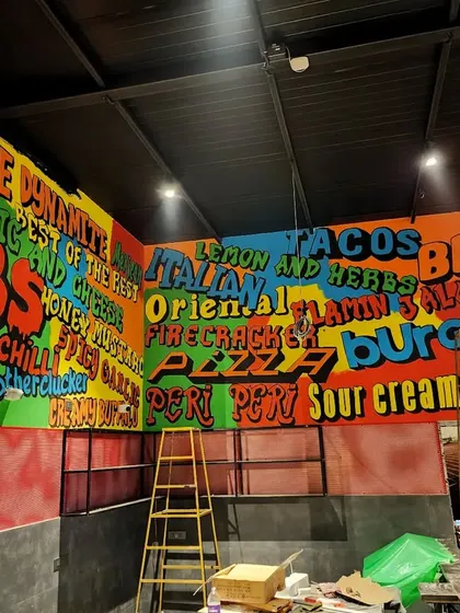 We turned the menu into art by painting it directly onto the walls in a vibrant, funky font. This wide shot shows the full scale of the typography mural.