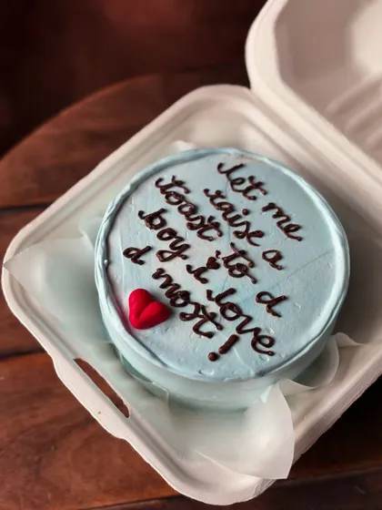 A sweet and romantic message on a cake: "let me raise a toast to a boy i love d most!" This light blue bento cake with a single red heart is a perfect personal gift.
