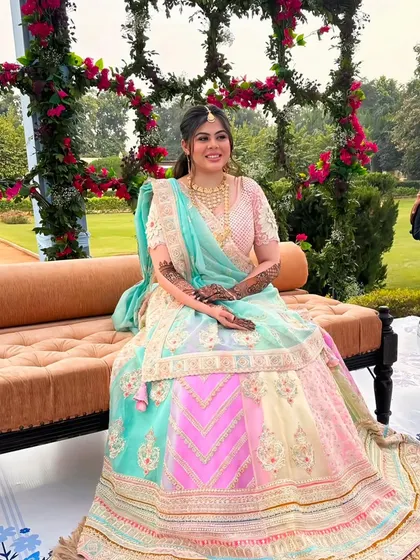 Another shot of the bride, this time seated, giving a full view of her gorgeous lehenga and the detailed mehndi on her hands.