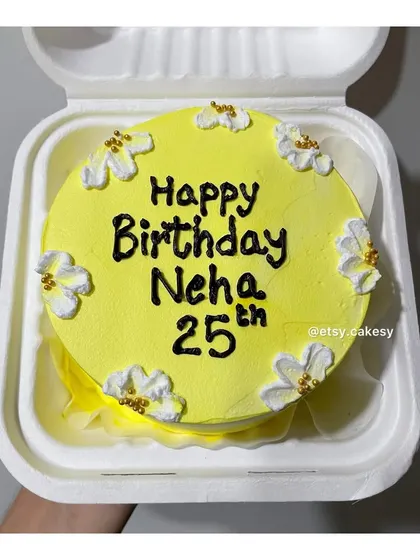 A cheerful yellow bento cake with white flowers for a 25th birthday.