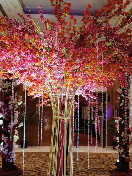 A statement floral tree with vibrant red and pink blossoms and hanging crystals, creating a canopy of dreams and a stunning focal point for the event.