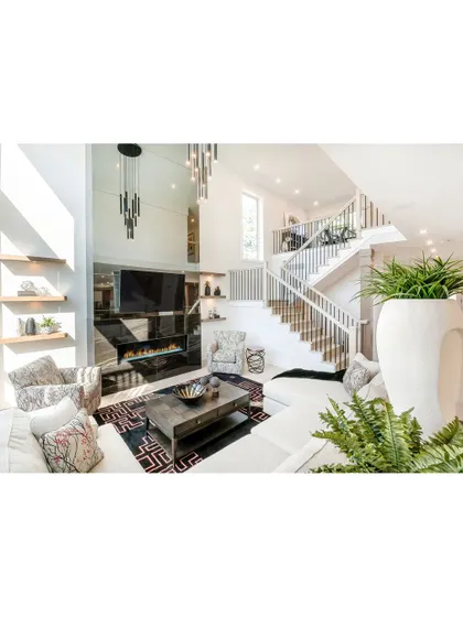 A bright, modern living room with a double-height ceiling and a statement media wall. We used a mirrored surface to enhance the sense of space and a cascading chandelier for a touch of glamour.
