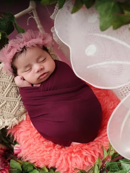 A close-up of the sleeping baby in the butterfly-themed setup. This angle highlights the delicate floral headband and the peaceful expression of the baby.