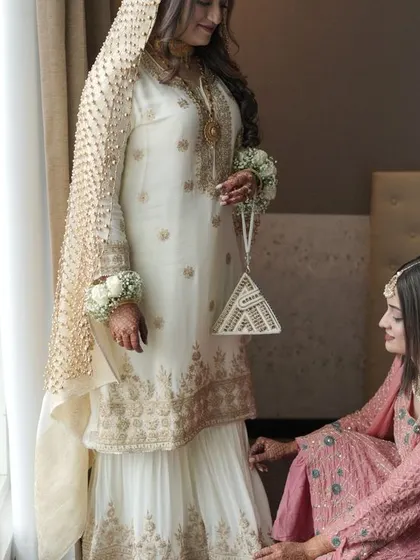A sister helps the bride with her outfit, a small, caring gesture that shows the support system surrounding the bride on her big day.