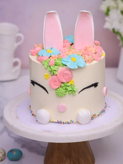 We craft an adorable centerpiece for your Easter feast with this sweet bunny face cake. With sleepy eyes, rosy cheeks, and tall pink ears peeking out from a crown of buttercream flowers, this cake is the essence of springtime charm.