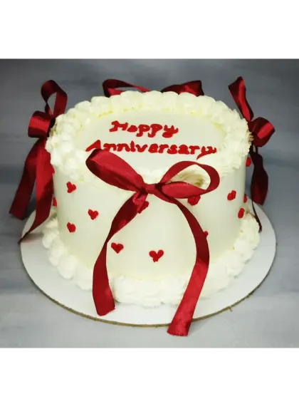 A classic anniversary cake with a vintage touch. This basic vanilla cake is decorated with delicate piping and beautiful red satin bows.
