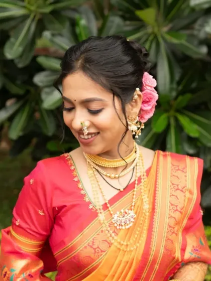 A close-up portrait showing the soft makeup and the traditional gold jewellery that completes the look.
