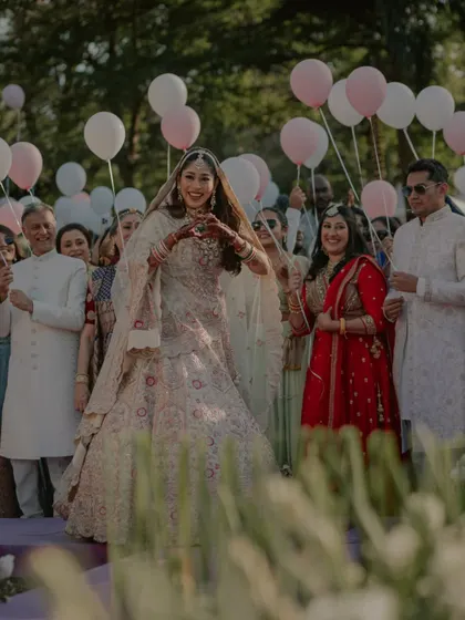 The bride's joyful entrance, making a heart shape with her hands as she walks down the aisle.