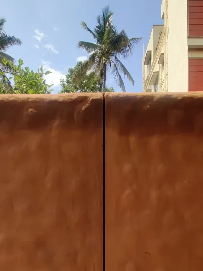 A close-up of a finished mud wall, showing its natural, earthy texture and warm color under the sun.