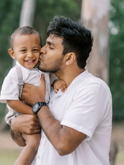 A father's kiss for his smiling two-year-old son. The love and affection between them is beautifully captured.