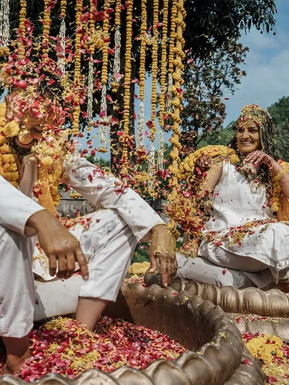 A playful moment during the Haldi ceremony, with the couple covered in turmeric and flower petals.