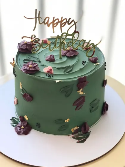 A sophisticated olive green cake with dark purple and pink abstract floral details.