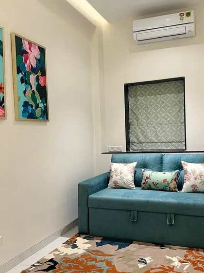 A cozy den in the South Mumbai residence, where a teal sofa bed is paired with vibrant floral artwork and a colorful rug. This multi-functional space is designed to be both stylish and practical.