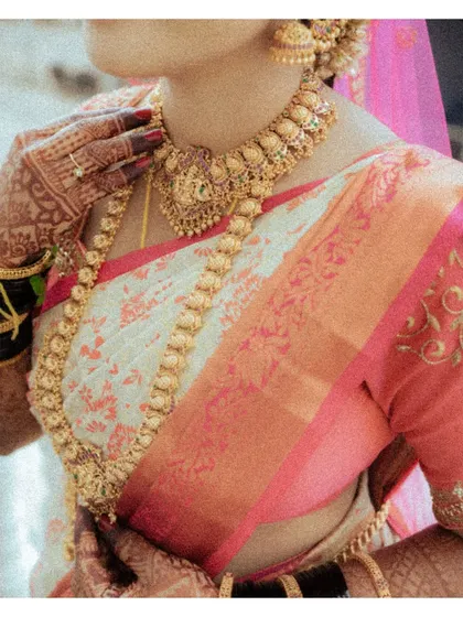 A detailed shot of a traditional South Indian bride's attire, focusing on her magnificent gold temple jewelry and silk saree.