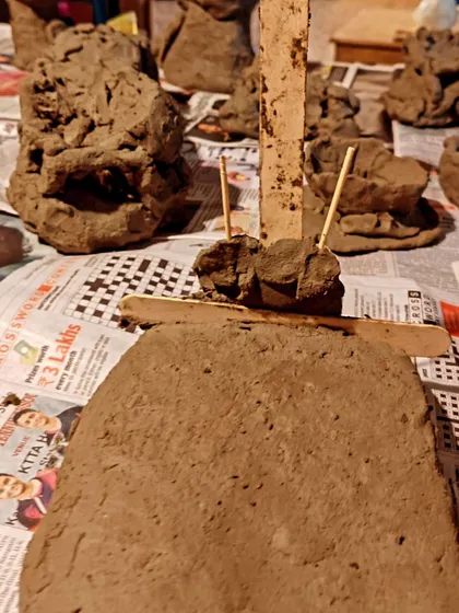 An array of clay sculptures, freshly made and drying on newspaper. Each piece is a unique expression of the child's imagination.