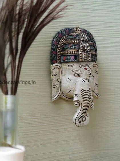 A small, 12-inch Ganesha head mask with an antique white finish and colorful accents. This piece is perfect for smaller spaces or as part of a gallery wall.