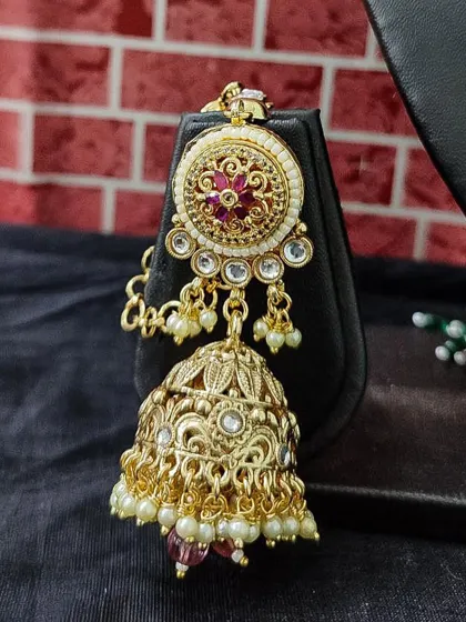 A detailed view of a rental jhumka with intricate filigree work and a floral top. The pearl drops add a classic finishing touch.
