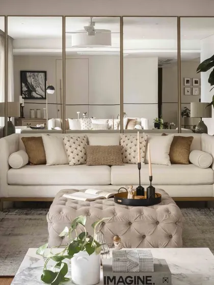 The combination of the tufted ottoman, marble coffee table, and layered sofas creates a rich, multi-textured living space.