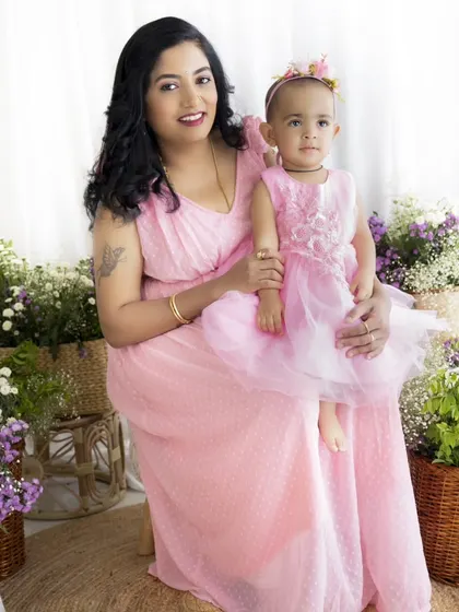 A classic mother-daughter portrait. The matching pink dresses and floral setting make this a perfect photo for Mother's Day.