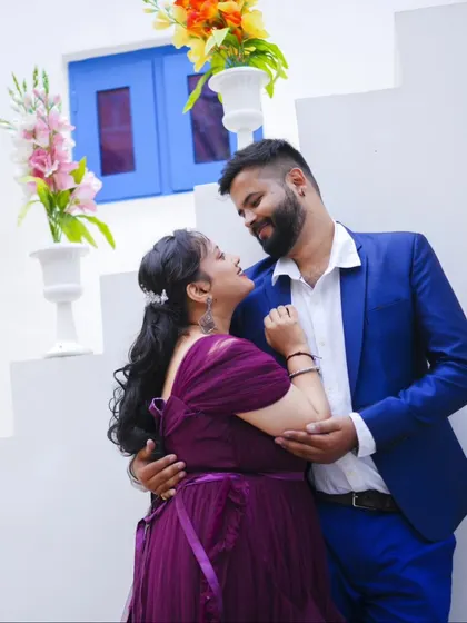 A romantic pre-wedding photo against a white and blue backdrop, with the groom-to-be looking lovingly at his partner.