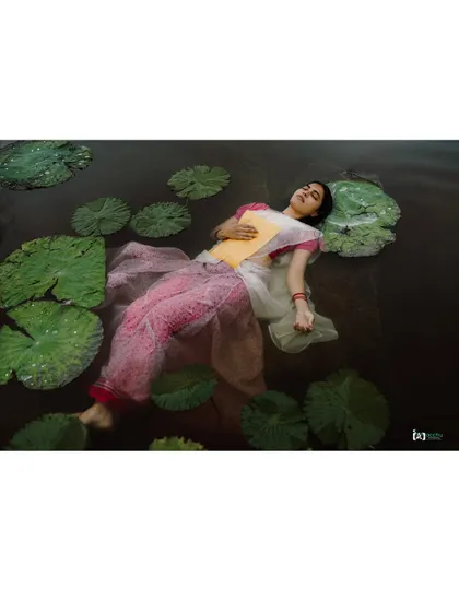 An artistic concept shoot inspired by Ophelia. The model floating in the water with lily pads creates a serene, painterly, and unforgettable image.