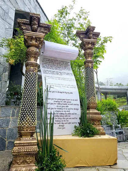 A unique decor piece featuring a large scroll with wedding vows, flanked by ornate golden pillars.