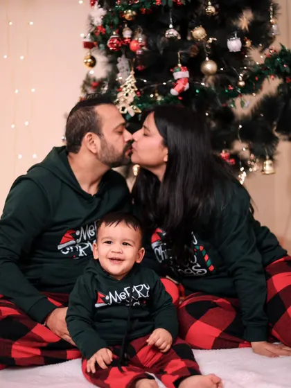 A sweet family Christmas portrait with matching pajamas and a kiss for the parents.