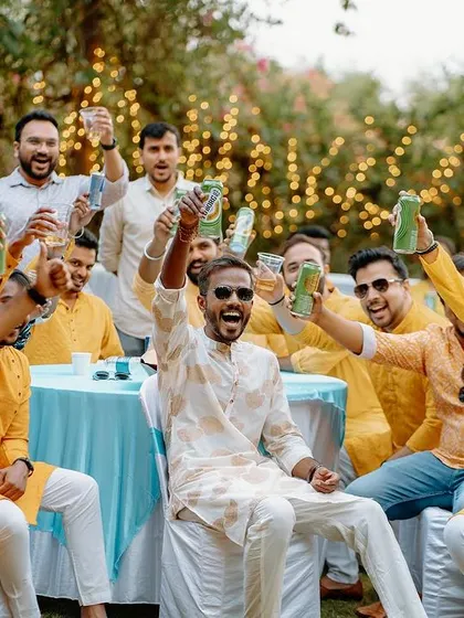 The groom and his friends raise a toast during the Haldi celebrations, a moment of camaraderie and fun.