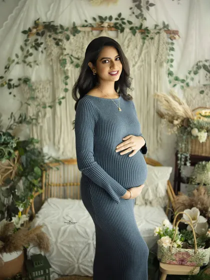 A simple and elegant portrait of a mother-to-be in a ribbed blue-grey gown. Her happy smile and the soft boho background create a warm and inviting image.