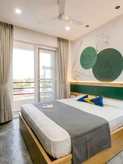 The master bedroom is a tranquil sanctuary with a soothing green and wood color palette. A hand-painted floral motif on the wall adds a personal, artistic touch.