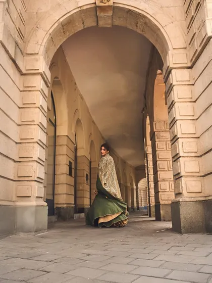 The grandeur of the outfit matches the setting. This shot emphasizes the dramatic flow of the jacket and skirt, creating a truly cinematic moment.