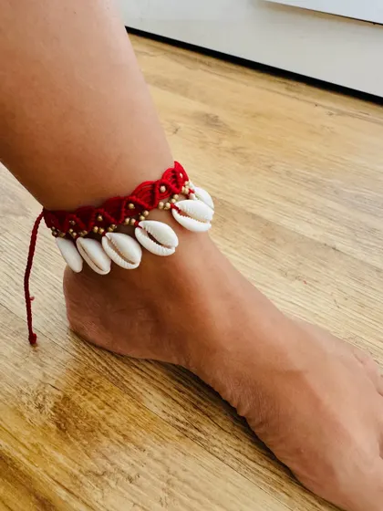 My red macrame shell anklet, worn to show how it looks. The design features real cowrie shells and is perfect for a bohemian, beachy style.