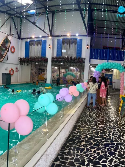 A wide view of a mermaid-themed party setup, showing how the decorations extend across the poolside, creating a cohesive and festive environment.