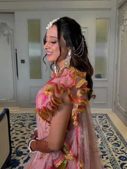 A playful Haldi look for Tanvi. We added glistening stones on her eyes for a touch of sparkle, complementing her bright pink and yellow outfit.