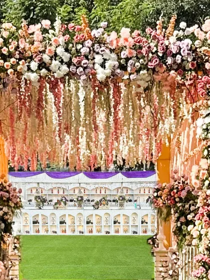 A grand entrance adorned with a canopy of peach and pink flowers, leading to the celebration within. This is how we welcome guests to your special day.