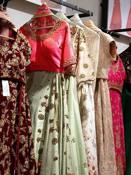 A close-up of some of the outfits available for rent, including a maroon velvet lehenga and a pastel green embroidered set.